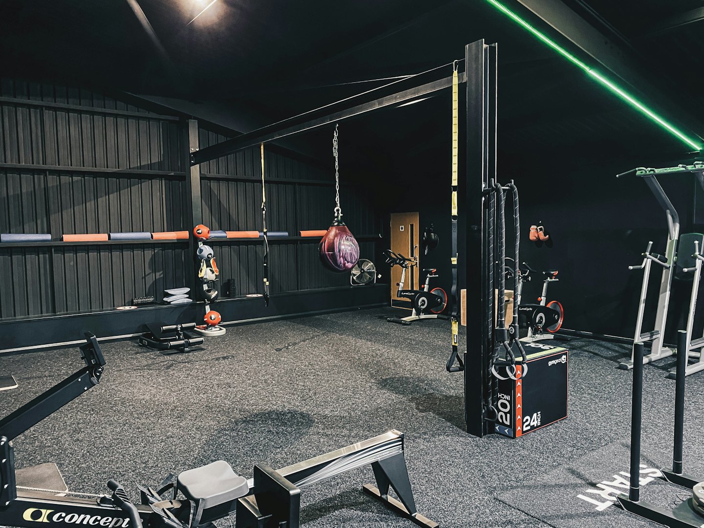 Modernt gym med roddmaskin, boxningssäck och cyklar.